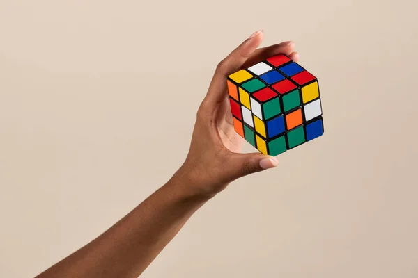 在米色背景下展示Rubik立方体尚未解决的脑筋急转弯的黑人女人的手 — 图库照片