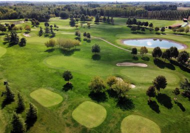 Aerial landscape of course of golf with green grassy meadows and ponds among trees in sunlight