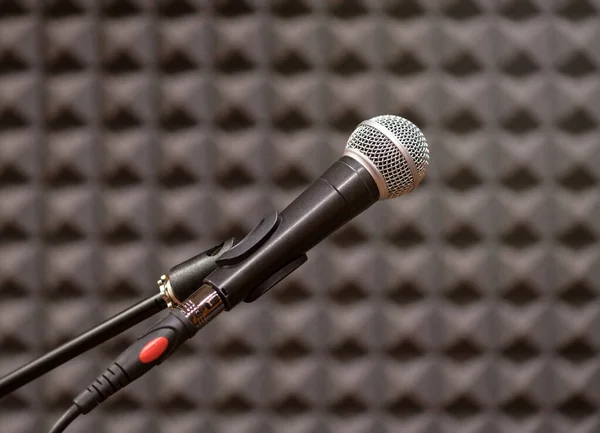 Contemporary microphone placed in rehearsal room against blurred black textured wall in selective focus