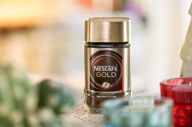 Nescafe coffee glass jar placed on table against blurred background of kitchen. Nestle product
