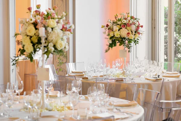 ガラス器と窓に対して花瓶に花を咲かせるエレガントな結婚式の宴会設定テーブル — ストック写真