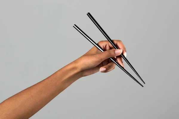 認識できない黒女性手保持中国語箸に対してグレー背景でライトスタジオ — ストック写真