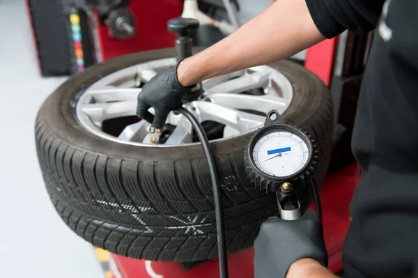 汽车维修车间用压力表抽吸平衡汽车轮胎的工人 — 图库照片