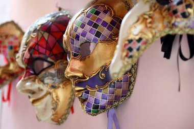 Venedik, İtalya 'da pembe duvarda asılı duran geleneksel Venedik karnaval maskelerinin profil görüntüsü.