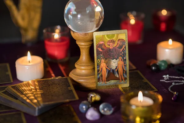 魔术球和点燃的蜡烛 与情人塔罗牌放在算命先生桌上的昏暗灯光下 免版税图库图片