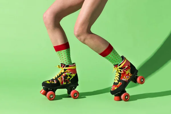 カラフルな靴下に匿名の若い女性の足のサイドビューライムカラースケートリンク上の影と光とロバスト調節可能なローラースケートに乗る — ストック写真