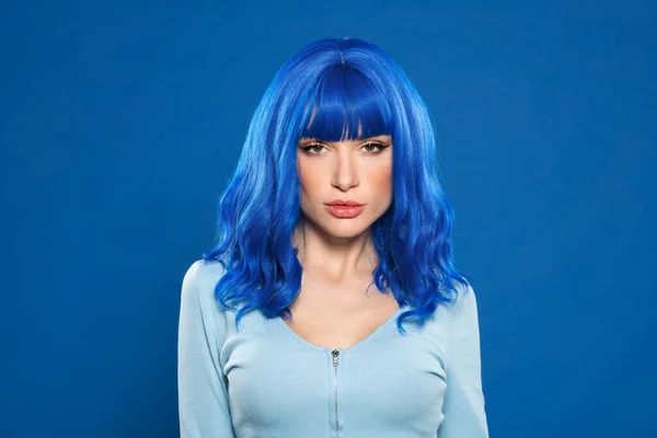 スタジオの鮮やかな背景に対してカメラを見ている深刻な青い髪の女性のヘッドショット — ストック写真