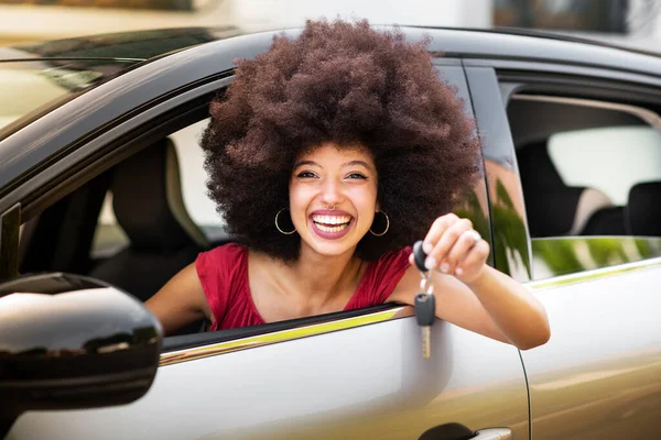 快乐的非洲裔美国女性 戴着非洲式的头发 面带微笑 坐在新车里看着相机 炫耀汽车钥匙 免版税图库图片