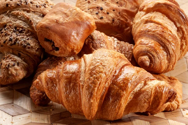 High angle of freshly baked croissants with sesame placed on wooden surface in bakery shop