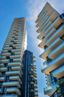 Milano İtalya 'da bulunan çok katlı gökdelenlerin dış yüzeyinden güneşli gün ışığında bulutlu mavi gökyüzüne karşı