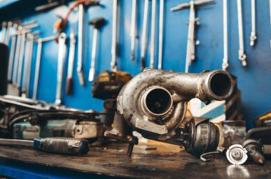 Otomobil turbo motor motorunun ve atölyede yedek parçaların kapatılması ve gün ışığında asılı donanım ve aletlere karşı tamir masasına yerleştirilmesi