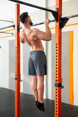 Bedensiz erkek kaslı sporcunun beden eğitimi çalışmasını tüm vücuda yansıtıyor. Spor salonundaki çıtayı yükselt.
