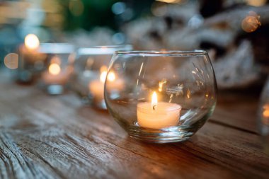 Ahşap masaya, bulanık arka plana konmuş yanan mumlarla dolu cam kaseler.