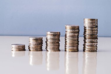 Beş gümüş para yığını yansıtıcı yüzeyde yükselen bir grafik oluşturuyor.