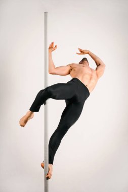 Kaslı erkek striptizci zarifçe aşk tanrısı pozunu tutuyor. Güç ve esneklik gösteriyor.