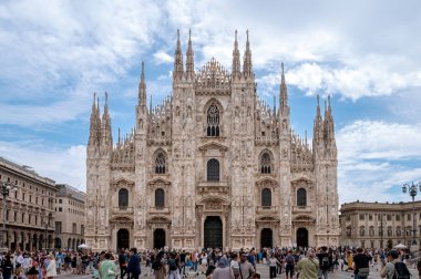 Duomo Meydanı 'nda yürüyen turistler, arka planda güneşli bir yaz gününde Duomo di Milano Katedrali' nin heybetli yüzüyle