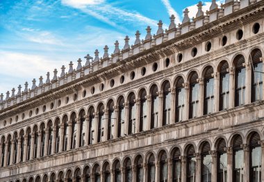 Tarihsel Procuratie Vecchie Piazza San Marco Venedik şehrinin dış cephesinde, Avrupa 'nın mavi gökyüzünün altında bulutlu kemerli pencereleri olan bir bina inşa ediyor.