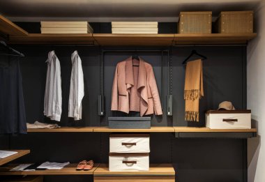 Contemporary walk in closet showcasing neatly arranged clothing, shoes, and accessories on wooden shelves and hanging racks clipart