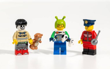 Lego iskeleti, uzaylı ve polis memuru minyatür figürleri beyaz arka planda duruyor, çeşitliliği ve içeriği temsil ediyor.