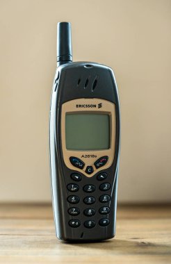 Eski Ericsson A2618 'lerin cep telefonu ahşap bir masanın üzerinde duruyor ve 2000' lerin başından kalma eski tasarım ve teknolojisini sergiliyor.