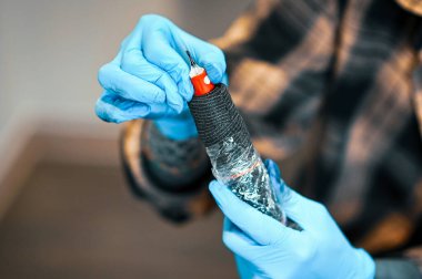 Dövme sanatçısı dövme makinesini hazırlıyor, iğne kartuş değiştiriyor, mavi eldiven, vücut sanatı ve tasarım giyiyor.