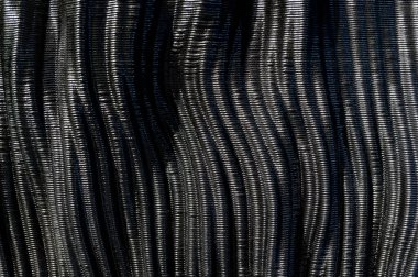 Parlak siyah karbon fiberin dalgalı dokusunu yakından inceleyerek zarif ve fütüristik bir zemin oluşturur.