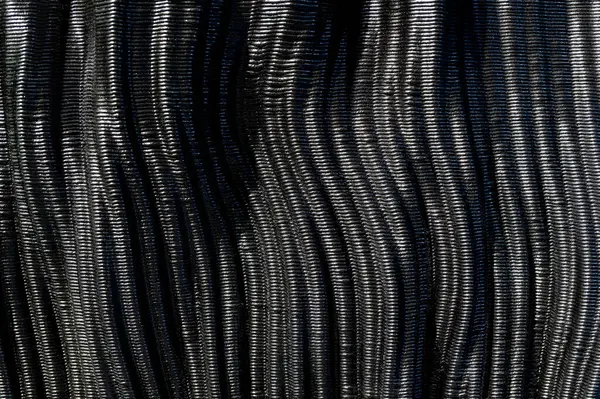 Parlak siyah karbon fiberin dalgalı dokusunu yakından inceleyerek zarif ve fütüristik bir zemin oluşturur.