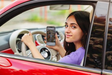 Direksiyon tutan ve GPS uygulamalı cep telefonu kullanan bir genç.