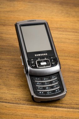 Eski Samsung SGH i750 sürgülü cep telefonu ahşap bir yüzey üzerinde, geriye dönük mobil teknoloji sergileniyor