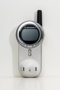 Motorola V70 model, beyaz arka planda duran genişletilmiş antenli bir cep telefonu.