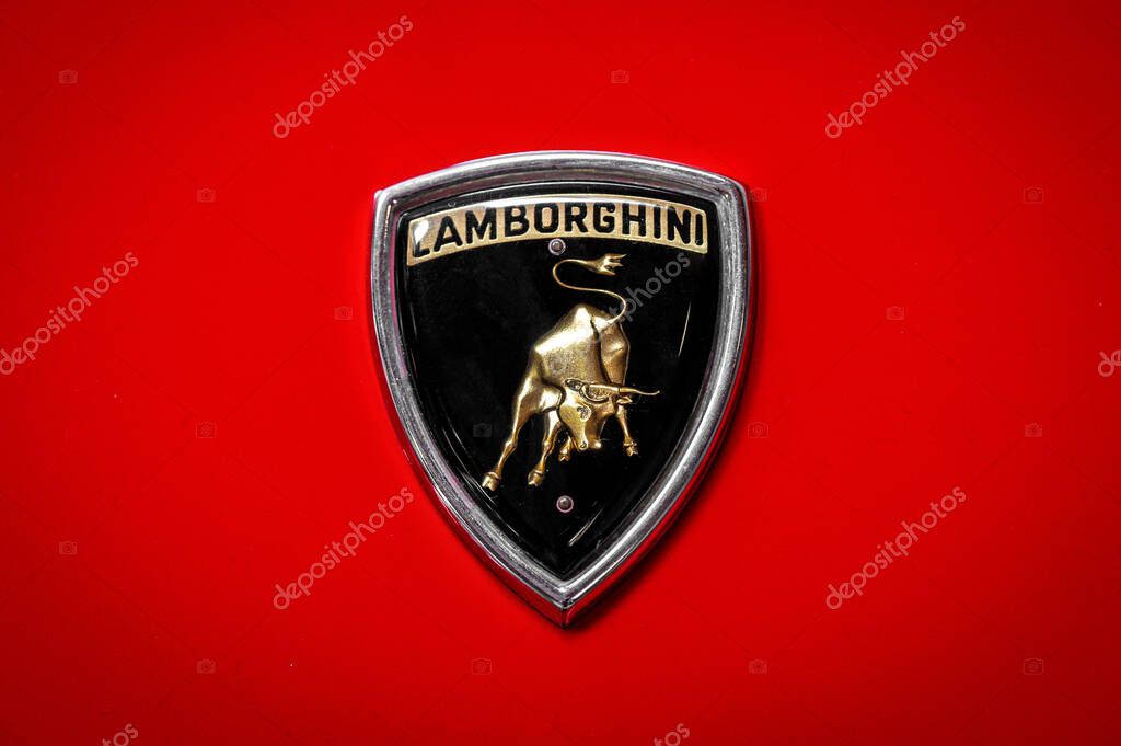 Somma Lombardo, Lombardy, Italy - May 15, 2025 : Close up of golden Lamborghini logo with bull emblem on a red vintage car