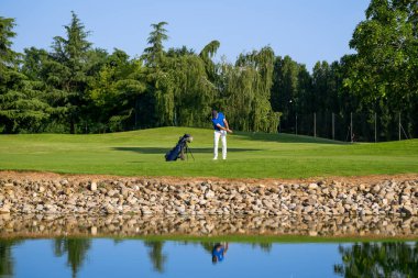 Güzel bir golf sahasında güneşli bir günde golf topuna vuran profesyonel bir golfçü.