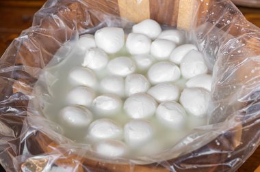 Küçük mozzarella topları tuzlu suya batırılmış ahşap bir çanak içinde satılmaya hazır.