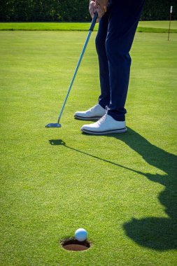 Golfçü, golf sahasında topu deliğe sokmak için golf sopası kullanır.