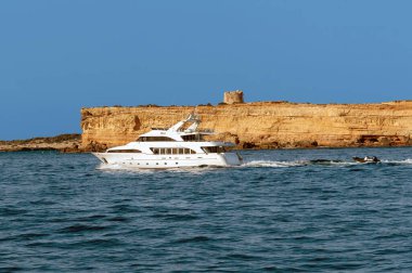 Lüks bir yat, bir uçurumun kenarında seyrediyor şefkatli takipçileriyle güneşli bir denizin tadını çıkarıyor.