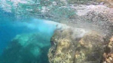 Deniz dalgaları kayalara çarpıyor ve kabarcıklar yaratıyor, sualtı çekimi, Aliki, Thassos, Yunanistan, aydınlık yaz günü, kristal berrak su