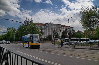 Sofya, Bulgaristan - 19 Nisan 2024: Perlovska nehri üzerinde bir köprü ile otomobiller, tramvay, tramvay rayları ve trafik ışıkları için bir caddesi olan antik binaların arka planına kıyasla kavşak manzarası, Sofya, Bulgaristan. Ziyaret yerinde..