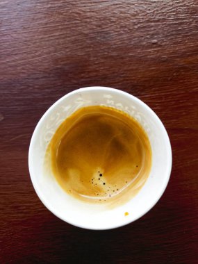 Tahta bir masanın üzerinde bir bardak kahve duruyor.