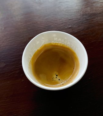 Tahta bir masanın üzerinde bir bardak kahve duruyor.