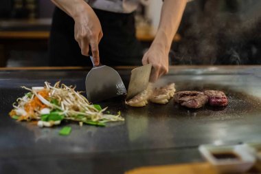 teppan show at a traditional Japanese restaurant. hands of the cook. Japanese cook prepares meat, fish, rice, vegetables for guests