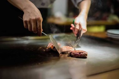 teppan show at a traditional Japanese restaurant. hands of the cook. Japanese cook prepares meat, fish, rice, vegetables for guests