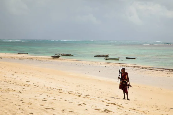 stock image Diani beach,Mombasa, Kenya. 14 oktober 2019.  beautiful resort area with a swimming pool and cozy white houses and tropical treesone happy african maasai man stands by the ocean and holds Afric