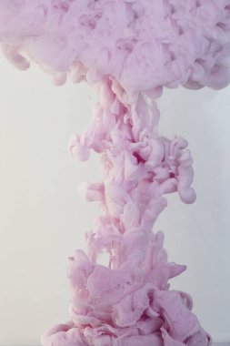 Mürekkep suya düştü ve hareket halindeyken fotoğrafını çekti. Suda fırıl fırıl dönen boya. Pembe bulut ve dumanı beyaz arka planda izole edilmiş suda..