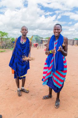 Kenya Afrika, 16 Ekim 2019. Afrika kabilesi Masai 'li erkekler geleneksel köylerinin arka planına karşı tam gelişim içinde.