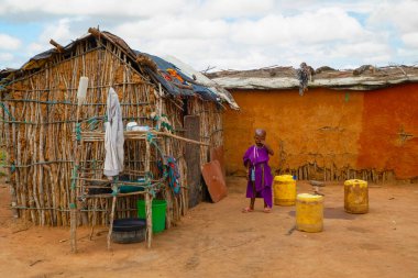 Kenya Afrika, 16 Ekim 2019, Masai kabilesinden küçük Afrikalı kız kil evinin yakınında duruyor.