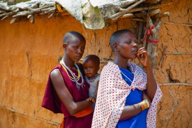 Kenya Afrika, 16 Ekim 2019. Afrika kabilesinden Maasai 'li kadınlar köydeki evlerinde kilden yapılmış ulusal elbiseler giyiyorlar.