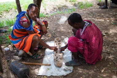 Kenya Afrika, 16 Ekim 2019. Maasai kabilesinin ulusal kıyafetli iki Afrikalı mancala oynuyor.