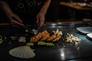 Geleneksel bir Japon restoranında Teppan gösterisi. Aşçının elleri. Japon aşçı sıcak masada et, balık, pirinç ve sebze hazırlar.