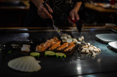 Geleneksel bir Japon restoranında Teppan gösterisi. Aşçının elleri. Japon aşçı sıcak masada et, balık, pirinç ve sebze hazırlar.