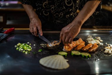 Geleneksel bir Japon restoranında Teppan gösterisi. Aşçının elleri. Japon aşçı sıcak masada et, balık, pirinç ve sebze hazırlar.